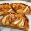 Blätterteig-Apfel-Tarte Rezept Zutaten: - Blätterteig - Äpfel - Zucker - Zimt - Butter - Zitronensaft - Ei - Mandelblättchen Anleitung: 1. Blätterteig ausrollen und in eine Tarteform legen. 2. Äpfel schälen, entkernen und in Scheiben schneiden. 3. Äpfel mit Zucker, Zimt und Zitronensaft vermischen. 4. Äpfel gleichmäßig auf dem Blätterteig verteilen. 5. Butter in kleine Stücke schneiden und auf die Äpfel legen. 6. Tarte im vorgeheizten Ofen bei 200 Grad backen. 7. Ei in einer Schüssel verquirlen und den Rand der Tarte damit bestreichen. 8. Mandelblättchen darüber streuen und weiterbacken, bis die Tarte goldbraun ist. 9. Abkühlen lassen und servieren.