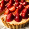 Erdbeertarte Rezept Zutaten: - 250 g Mehl - 125 g Butter - 75 g Zucker - 1 Ei - 500 g Erdbeeren - 250 g Sahne - 1 Päckchen Vanillezucker - 2 EL Puderzucker Anleitung: 1. Mehl, Butter, Zucker und Ei in eine Schüssel geben und zu einem Teig verkneten. 2. Den Teig in eine Tarteform drücken und einen Rand formen. 3. Den Teig 30 Minuten im Kühlschrank ruhen lassen. 4. Den Ofen auf 180 °C vorheizen und den Teig 20 Minuten backen. 5. Die Erdbeeren waschen und in Hälften schneiden. 6. Die Sahne mit dem Vanillezucker steif schlagen. 7. Den gebackenen Teig auskühlen lassen und die Sahne darauf verteilen. 8. Die Erdbeeren darauf anrichten und mit Puderzucker bestäuben.
